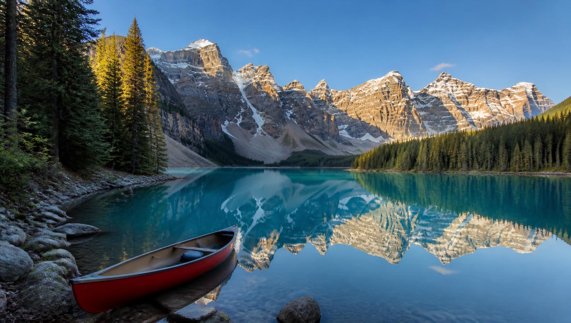 A turquoise glacial lake ringed by pine forest and snow-capped peaks in the Canadian Rockies