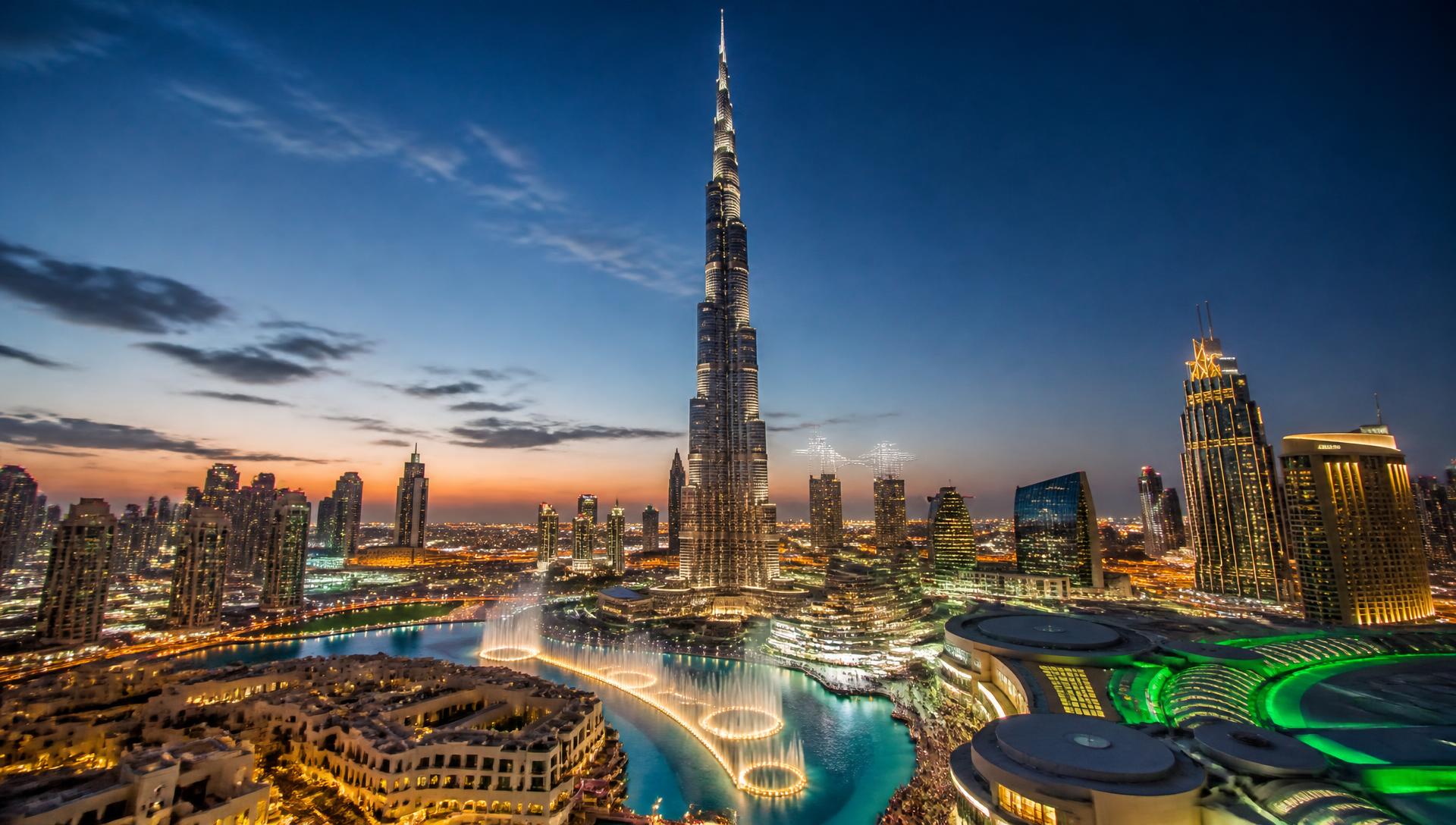 The Burj Khalifa rising above the lit Downtown Dubai skyline and fountain lake at dusk