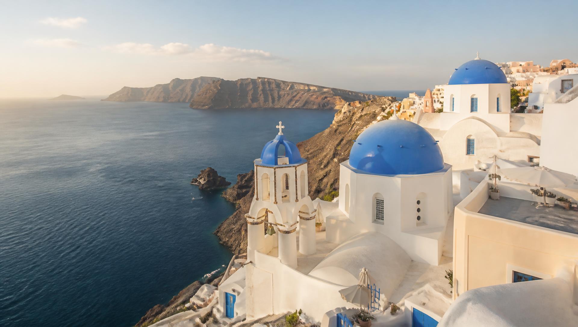 Whitewashed Cycladic village with blue-domed churches above the deep blue Aegean sea